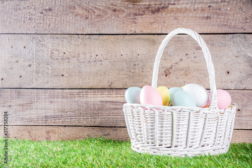 Colorful pastel Easter eggs on green and wooden garden terrace.  Funny spring decoration. Happy Easter greeting card background.