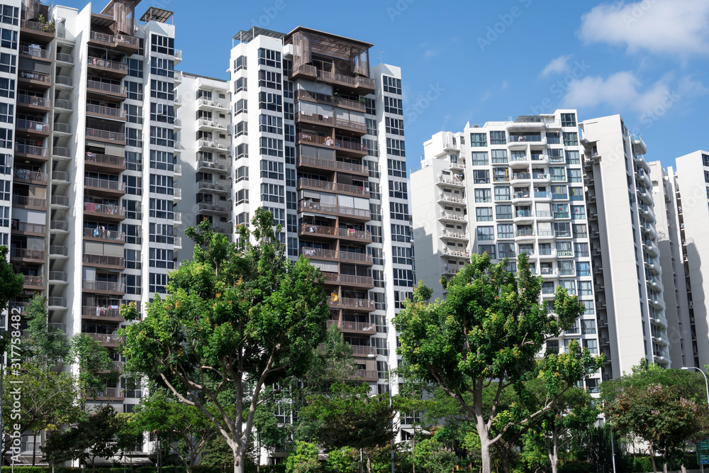Frontal shot of residential condominium with green trees in front