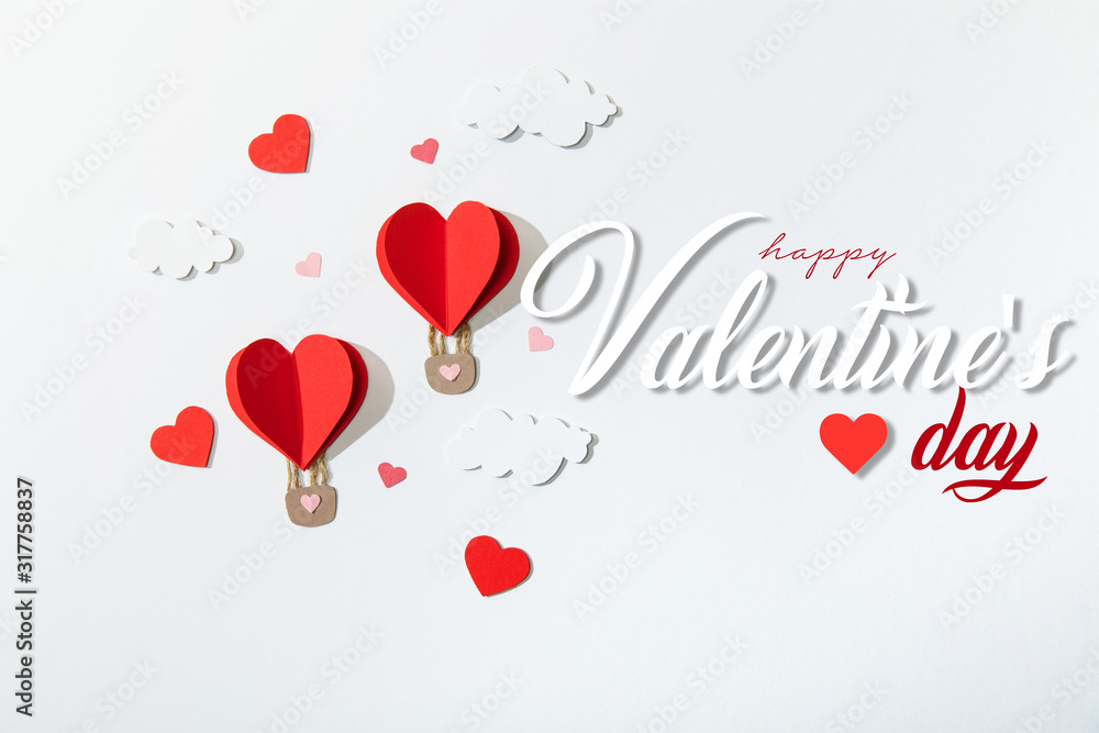 top view of paper heart shaped air balloons in clouds near happy valentines day lettering on white background