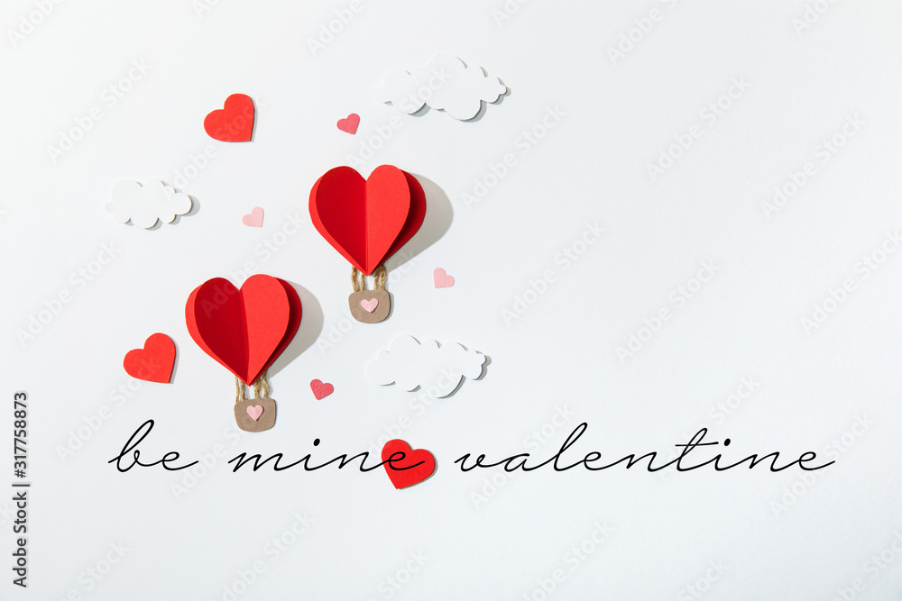 top view of paper heart shaped air balloons in clouds near be mine valentine lettering on white background