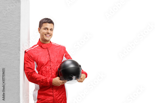 Male racer leaning against wall and holding a helmet