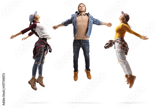 Fototapeta Naklejka Na Ścianę i Meble -  Two young women and a guy performing a dance jump