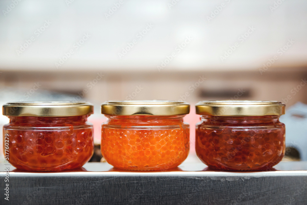 Variety of red caviar on the counter in a fish shop. Tasty salmon caviar, trout caviar and pink salmon caviar in jars. Variety of red caviar on the counter in a fish shop. Tasty salmon caviar, trout caviar and pink salmon caviar in jars.