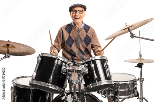 Tela Senior drummer with a drum set smiling at the camera and playing with drumsticks
