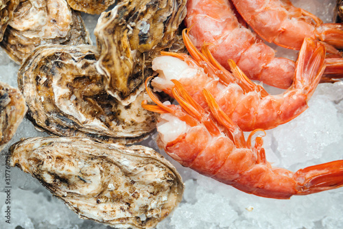 Fresh seafood like oysters and shrimps on a ice, close up. Healthy seafood concept. Retail display at fish market.