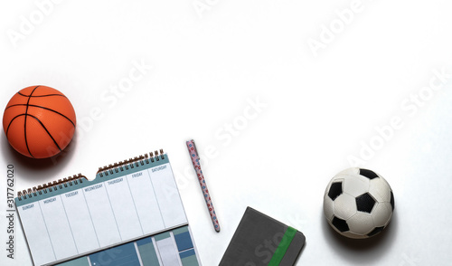 Top down view of a weekly workout plan or sports schedule with basketball and soccer ball