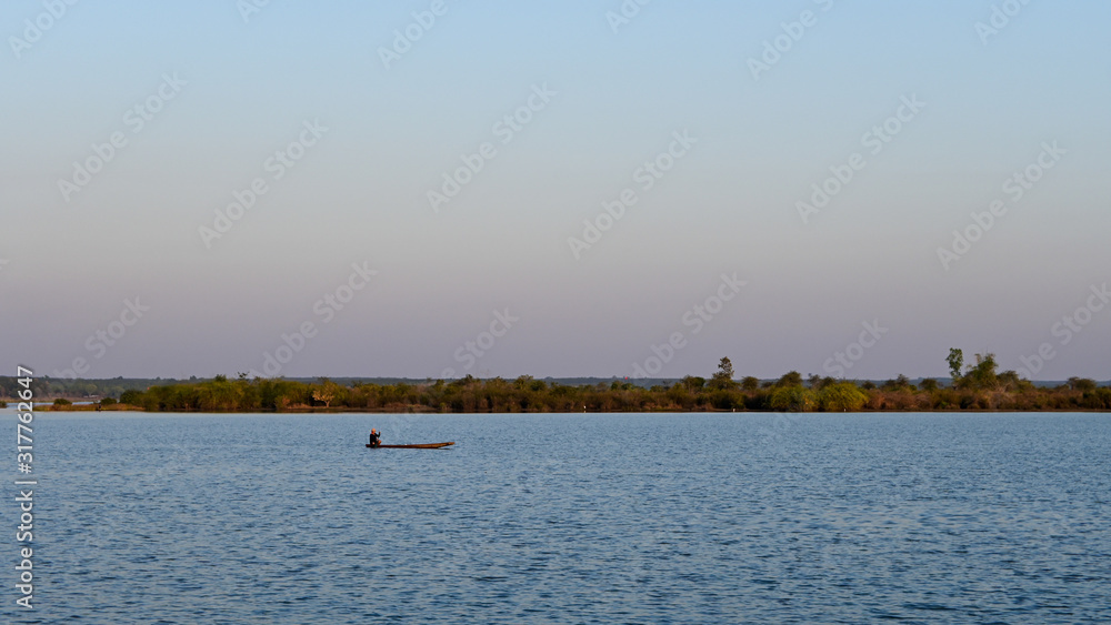 Scenic View Of Lake With Fisherman Against Sky