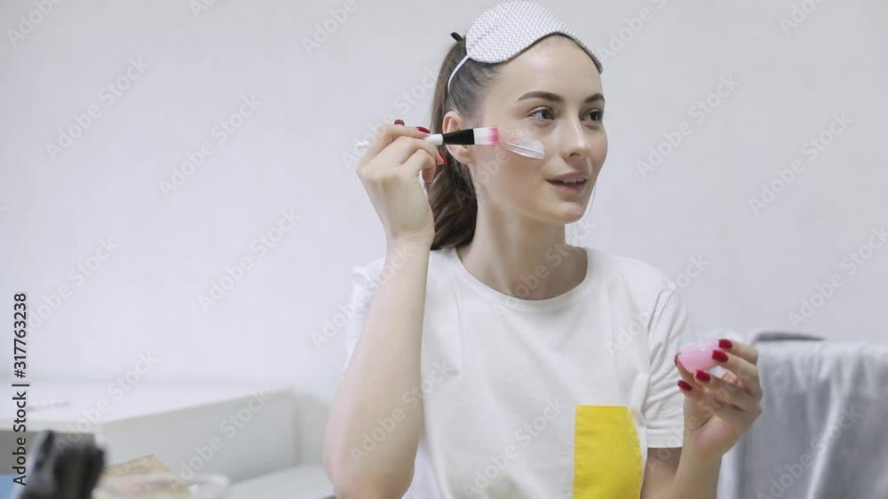 Close-up of smilingirl with headband on the head applying a cleansing clay mask on face Close-up of smilingirl with headband on the head applying a cleansing clay mask on face