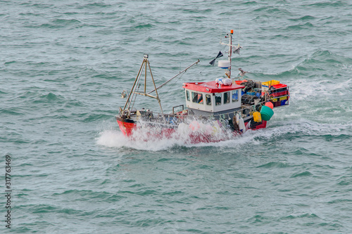 Fototapeta Fishing Boat splashing through the choppy sea