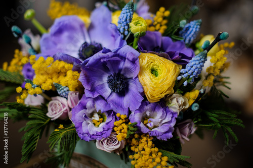Box full of purple tender color flowers and yellow mimosa decorated with green leaves