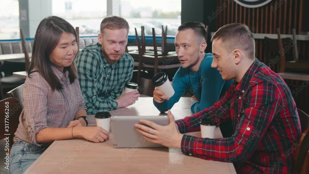 Young friends using digital tablet while drinking coffee in coffee shop Young friends using digital tablet while drinking coffee in coffee shop