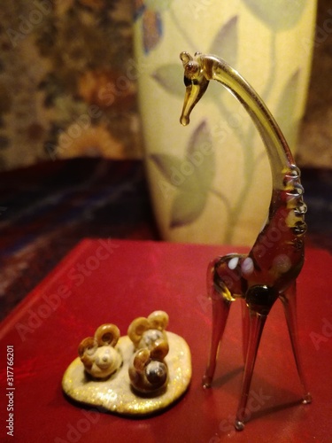 Glass giraffe looks at mice made from shells