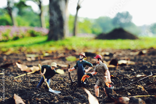 Miniature farmer is digging the soil to plant trees Taking care of preserving the environment and the world by planting trees, selective focus at miniature people 