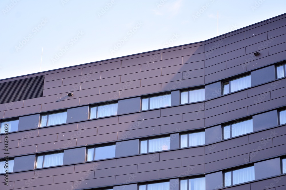 A view at a straight facade of a modern building with a dark grey facade. A view at a straight facade of a modern building with a dark grey facade.