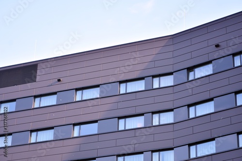 A view at a straight facade of a modern building with a dark grey facade.