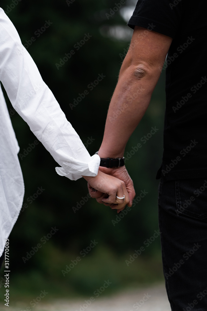 A man next to a woman, guy and a girl are standing close, touching each other, holding hands. The concept of first teenage love. Boy and girl, couple. Intimacy, honesty, trust. Bright future. Couple