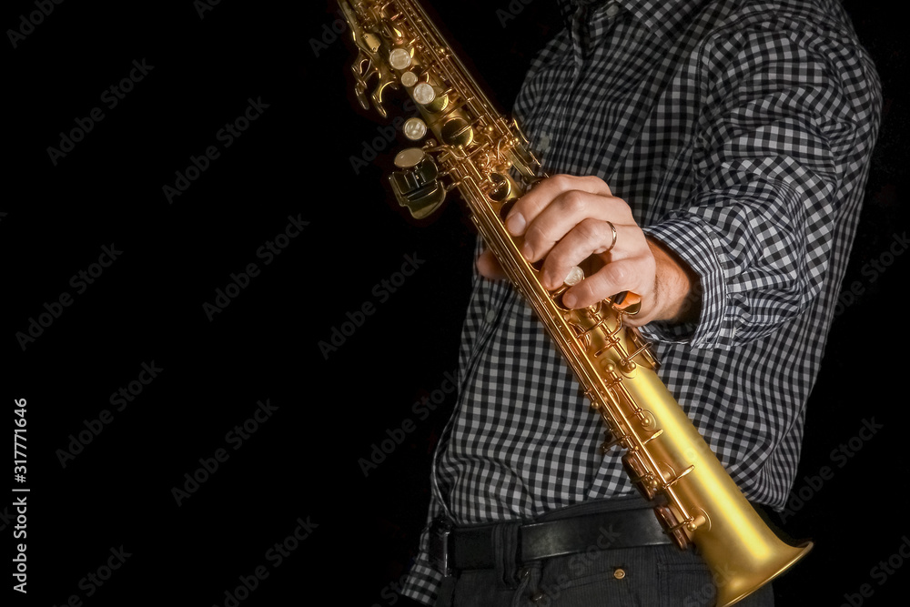 Naklejka premium soprano saxophone in hands on a black background