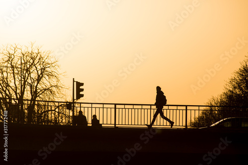  silhouette of man running on the bridge by sunset