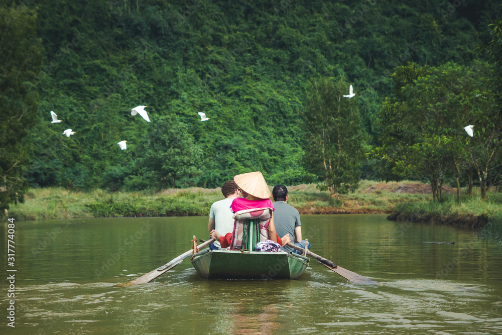 Ninh Binh in Vietnam. Boat on Tam Coc river. Birds flying around. Animals wildlife paradise. Tourists on a boat with a guide. Ninh Binh in Vietnam. Boat on Tam Coc river. Birds flying around. Animals wildlife paradise. Tourists on a boat with a guide.