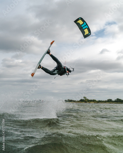 Wide angle shot of a kitesurfer doing an unhooked trick with the kite in the frame on an overcast day at the baltic sea
