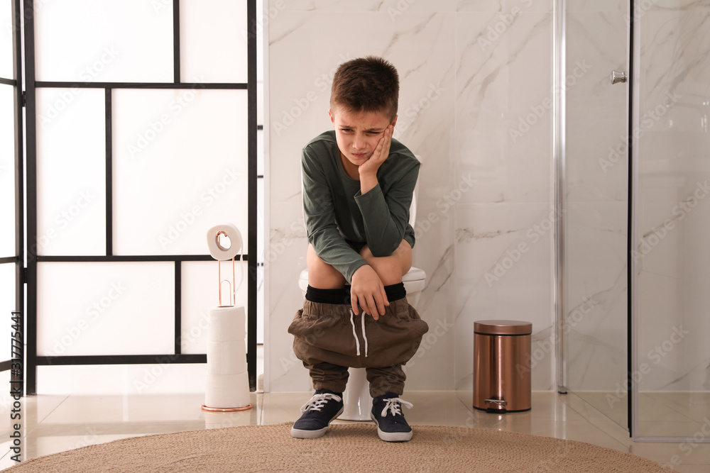 Boy suffering from hemorrhoid on toilet bowl in rest room foto de Stock
