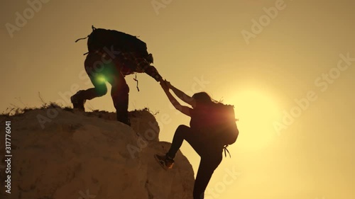 Happy family. Team work in business and life. A man holds out a helping hand to a girl while climbing to a height. The path to success and victory. Team Success Concept