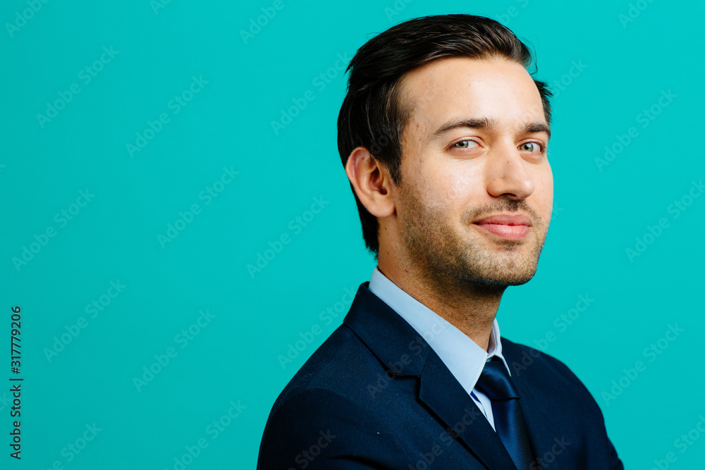 Serious head shot of a young adult entrepreneur businessman, isolated on blue studio background Serious head shot of a young adult entrepreneur businessman, isolated on blue studio background