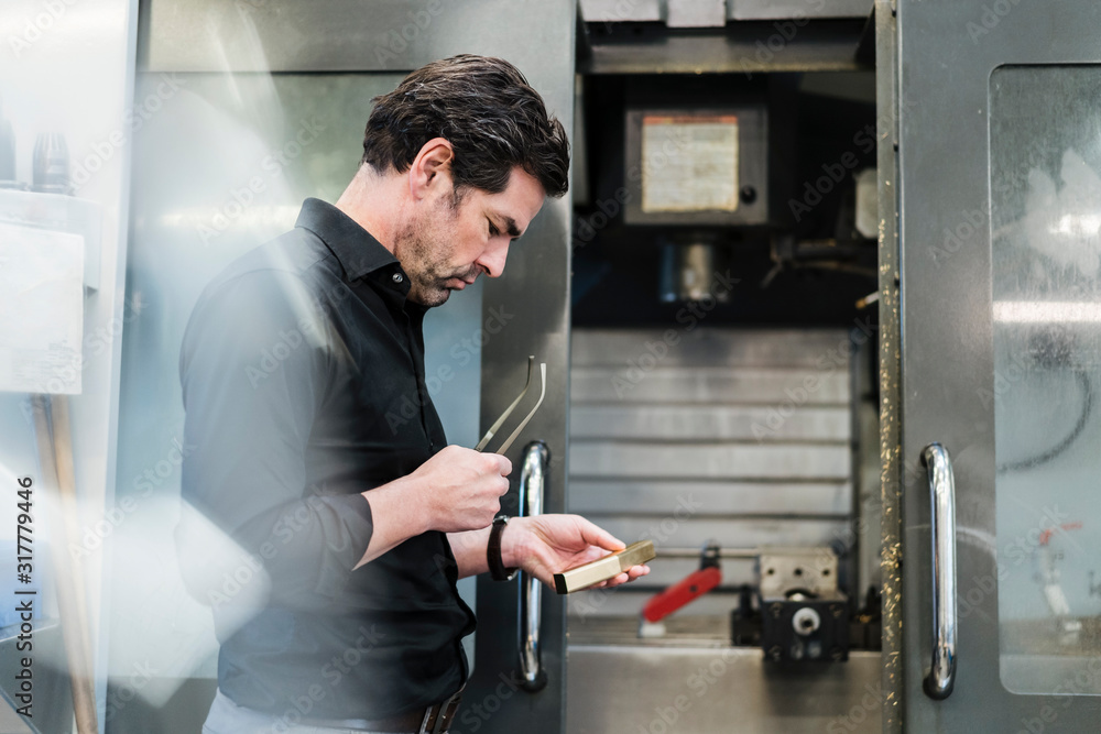 Businessman examining workpiece in a factory Businessman examining workpiece in a factory