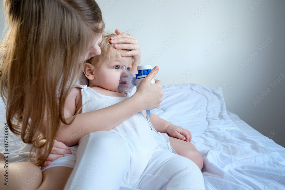 The children got sick. The older sister takes care of her brother and holds a gmu mask for inhalation. Medicine at home. stylish white room The children got sick. The older sister takes care of her brother and holds a gmu mask for inhalation. Medicine at home. stylish white room