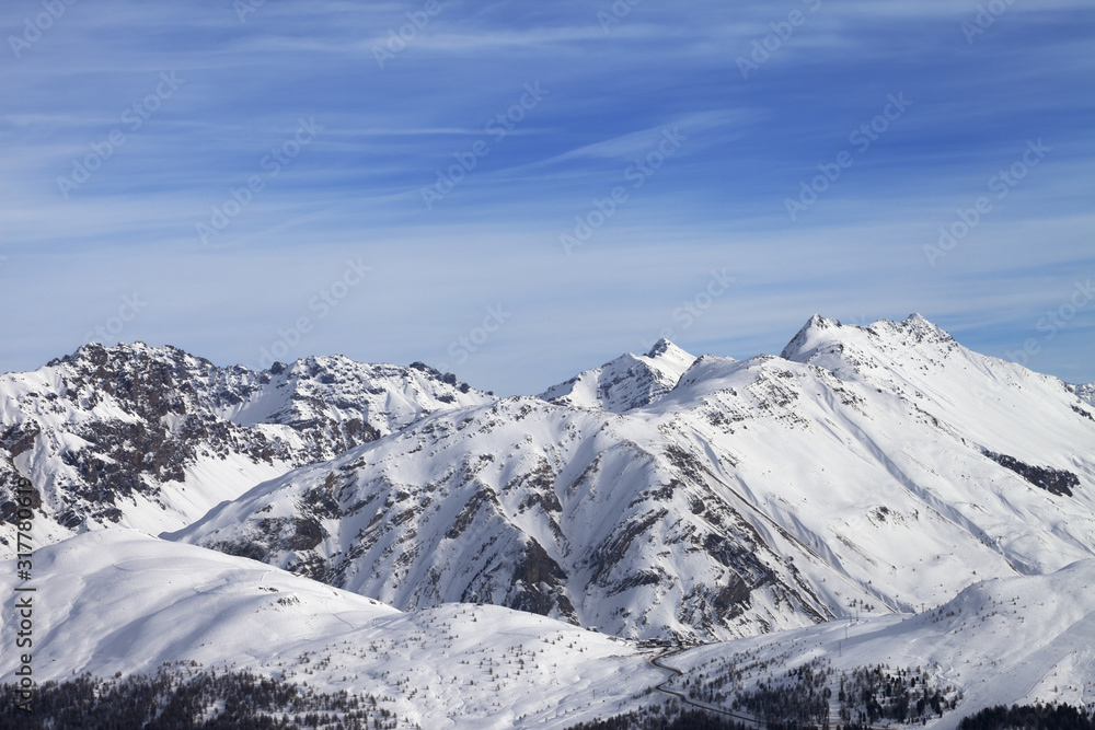 Snowy slope in high winter mountains and beautiful sunlit cloudy sky Snowy slope in high winter mountains and beautiful sunlit cloudy sky