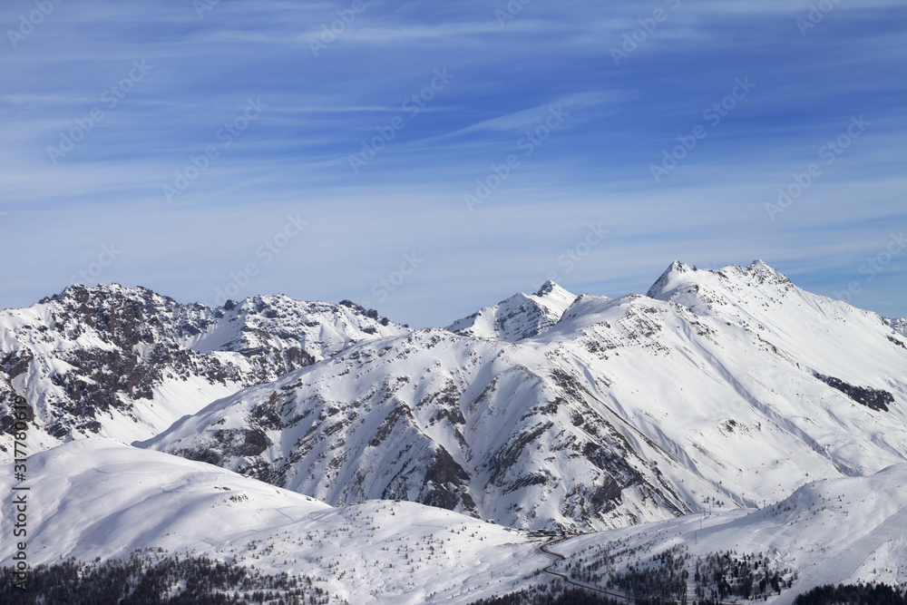 Snowy slope in high winter mountains and beautiful sunlit cloudy sky