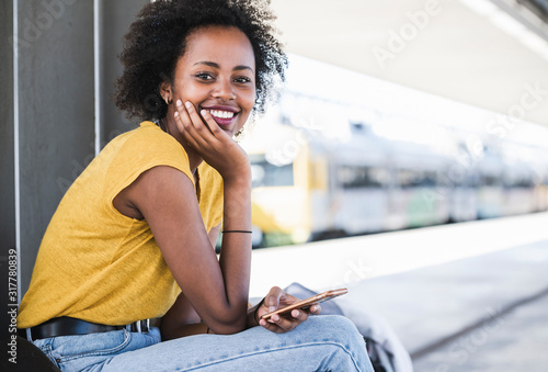 Portrait of smiling young woman with cell phone at the train station photo