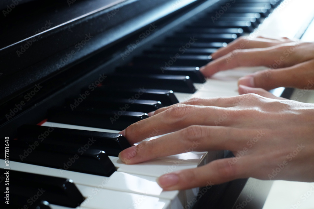 Fototapeta premium Close up of a music performer's hand playing the piano