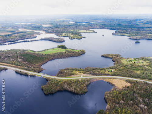 Beautiful view from a road going through the beautiful lake and forest, surrounded with water on both sides, shot above from drone, aerial vibrant picture