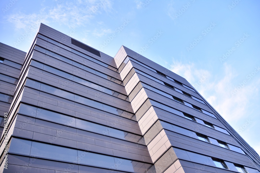 A view at a straight facade of a modern building with a dark grey facade. A view at a straight facade of a modern building with a dark grey facade.