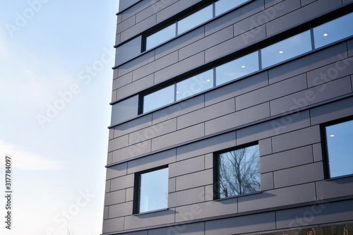 A view at a straight facade of a modern building with a dark grey facade.