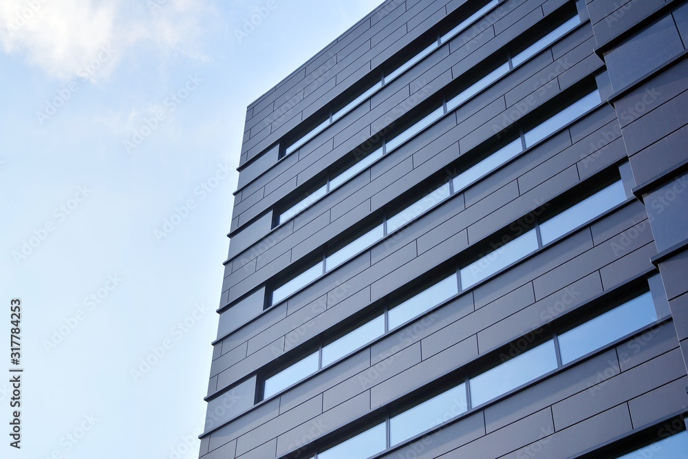 A view at a straight facade of a modern building with a dark grey facade. A view at a straight facade of a modern building with a dark grey facade.