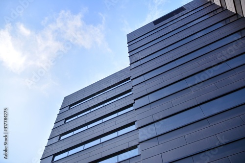 A view at a straight facade of a modern building with a dark grey facade.