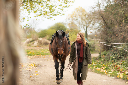 young horsewoman with a horse outeside walking photo