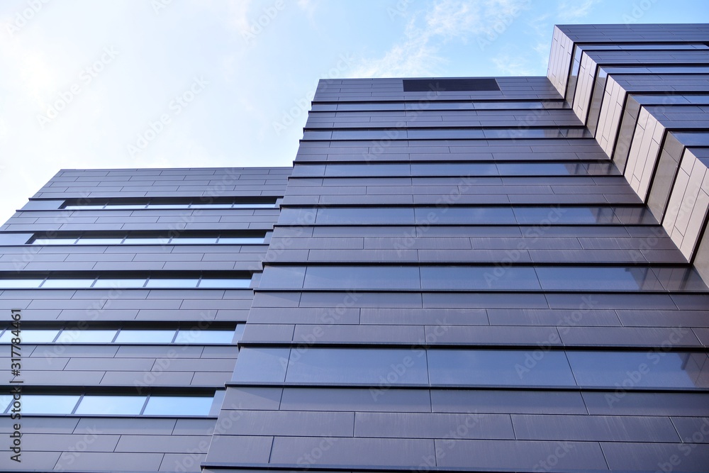 A view at a straight facade of a modern building with a dark grey facade. A view at a straight facade of a modern building with a dark grey facade.