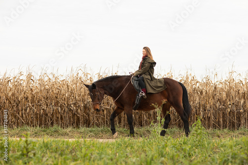 young horsewoman with a horse outeside riding photo