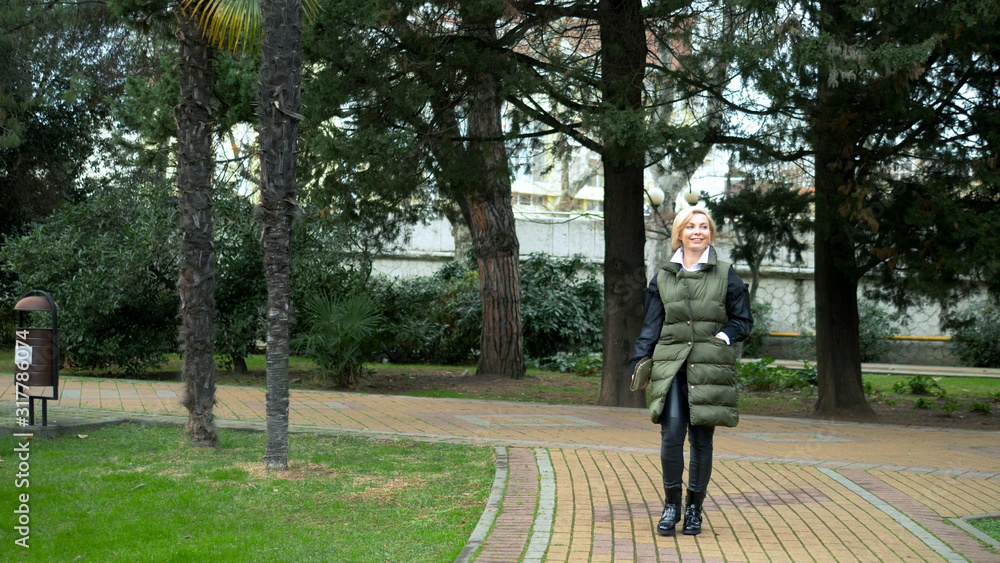 beautiful stylish trendy blond woman walking in a city Park in autumn