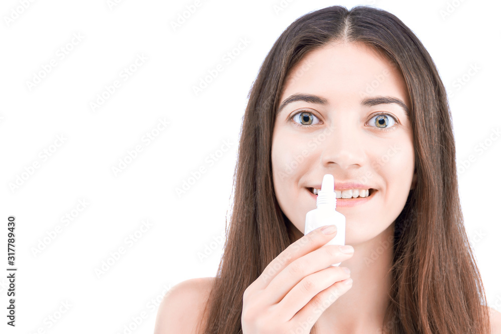 Smiling brunette girl is holding little white bottle with healing drops. Young woman is going to drip medication inside. Cold and flu, runny nose concept. Rhinitis treatment and allergy. Smiling brunette girl is holding little white bottle with healing drops. Young woman is going to drip medication inside. Cold and flu, runny nose concept. Rhinitis treatment and allergy.