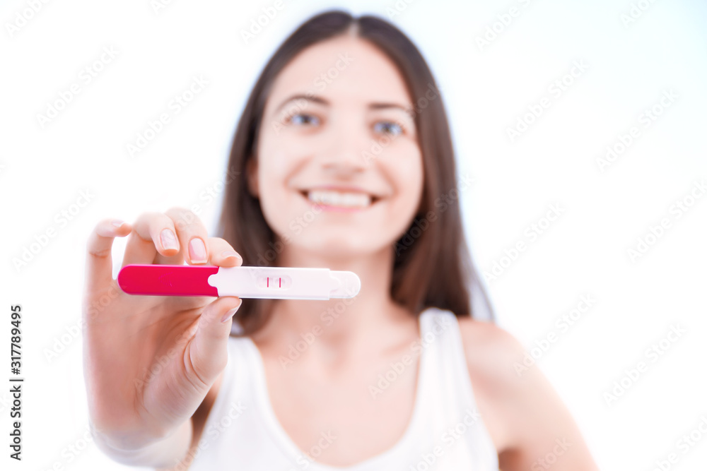 Young woman is holding medical test, tool for determine gestation. Girl is glad happy to see result of two red stripes. Female will be mom soon. First trimester of pregnancy and maternity concept. Young woman is holding medical test, tool for determine gestation. Girl is glad happy to see result of two red stripes. Female will be mom soon. First trimester of pregnancy and maternity concept.