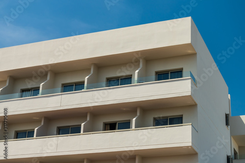 Modern new building with open balconies against the summer blue sky