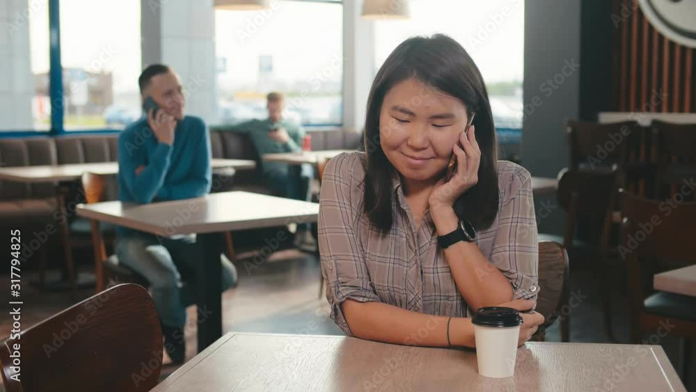 Asian female with having talking conversation with mobile phone while rest in cafe Asian female with having talking conversation with mobile phone while rest in cafe