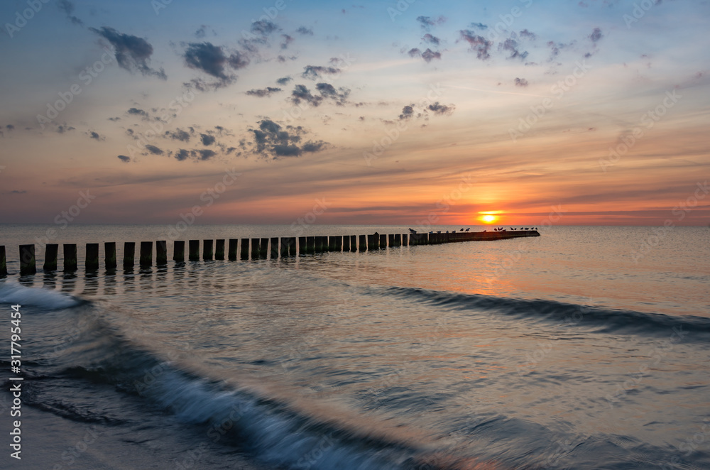 Baltic sea seascape at sunset, Poland, wooden breakwater and waves