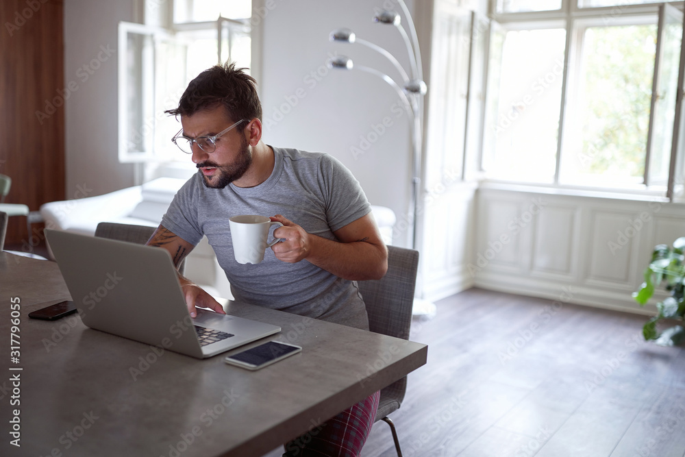 man having breakfast while working on laptop. man having breakfast while working on laptop.