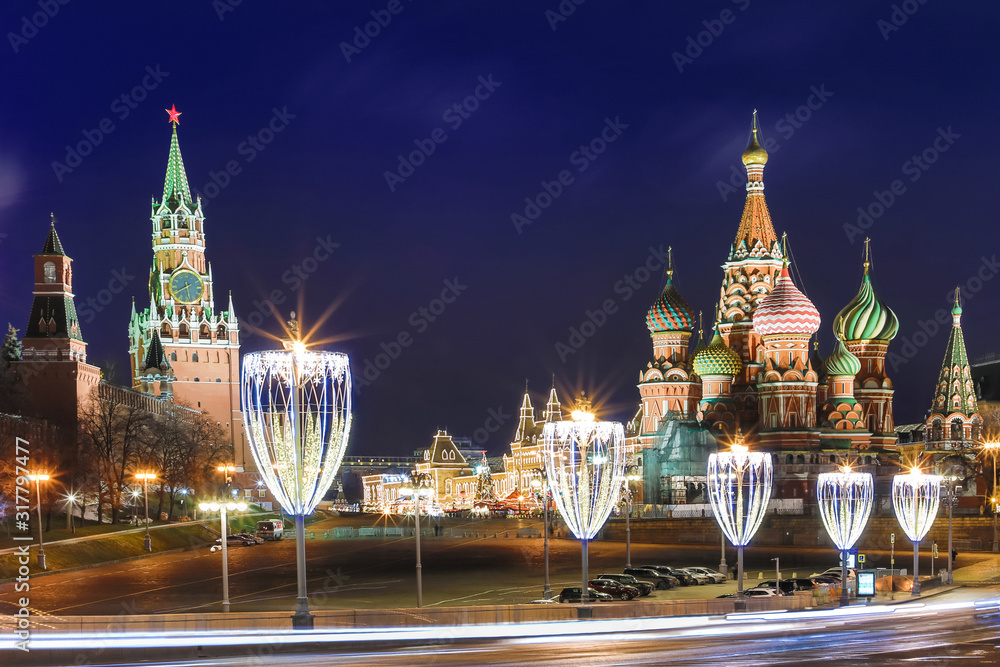 View on the illuminated Cathedral of Vasily the Blessed and towers of Moscow Kremlin on the Red square in Moscow, Russia in the cloudy night from the illuminated Bolshoy Moskvoretsky Bridge 