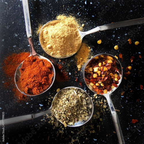 spices and herbs on silver spoons. chilli pepper, ginger, paprika, italian herbs. Kitchen flat lay design